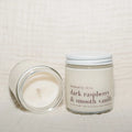 Candle and jar labeled 'dark raspberry & smooth vanilla' on a light background