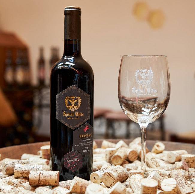 Bottle of Spirit Hills wine with a wine glass on a table with corks