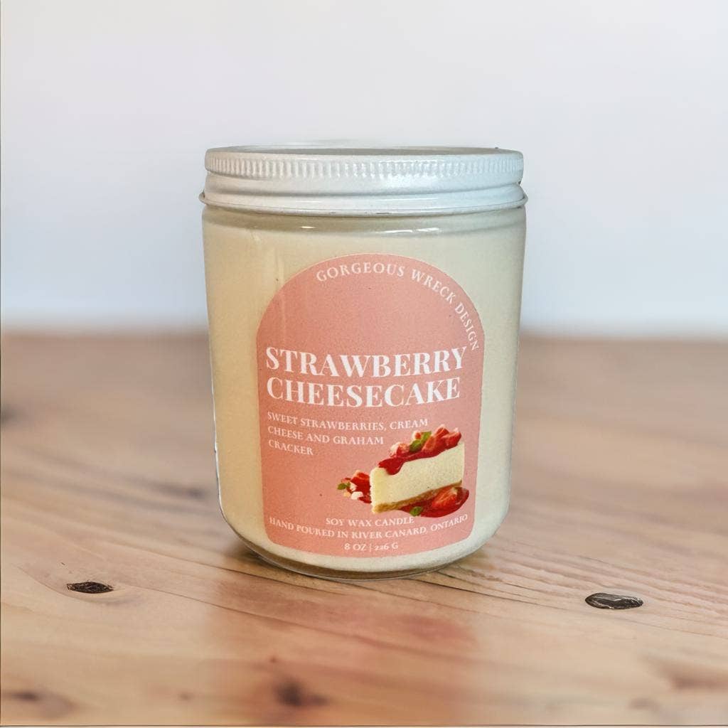 Jar of strawberry cheesecake candle on a wooden surface with a white background