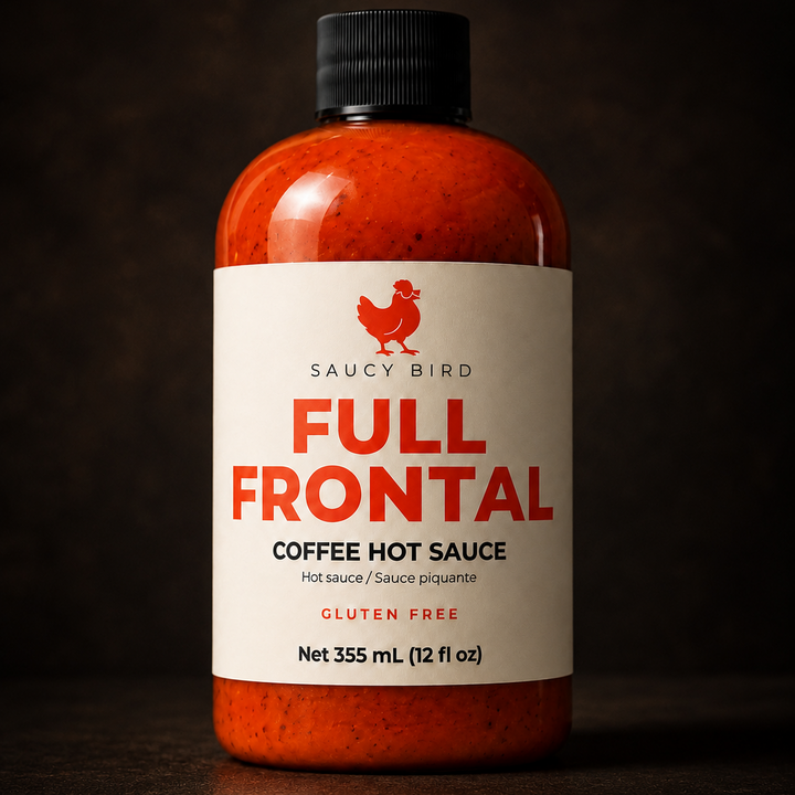 A bottle of Saucy Bird Full Frontal Coffee Hot Sauce, 355 mL (12 fl oz), featuring a white label with red text and a black cap, set against a dark, moody background.