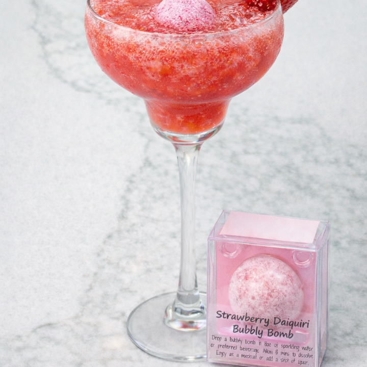 Strawberry daiquiri bubbly bomb in a glass with a strawberry on a marble surface