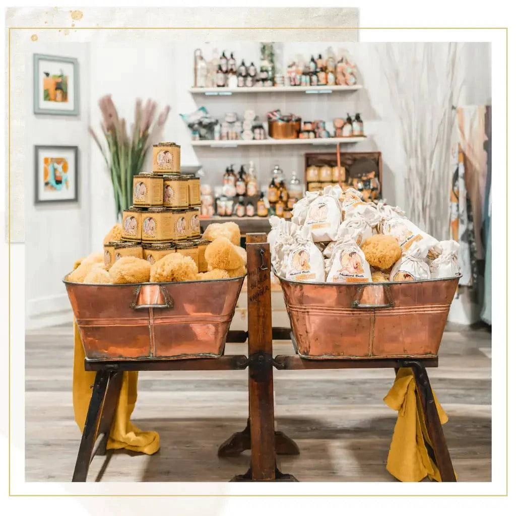 Barefoot Venus Mustard Bath Soak in a clear glass jar with a wooden scoop, surrounded by natural bath salts and herbs.