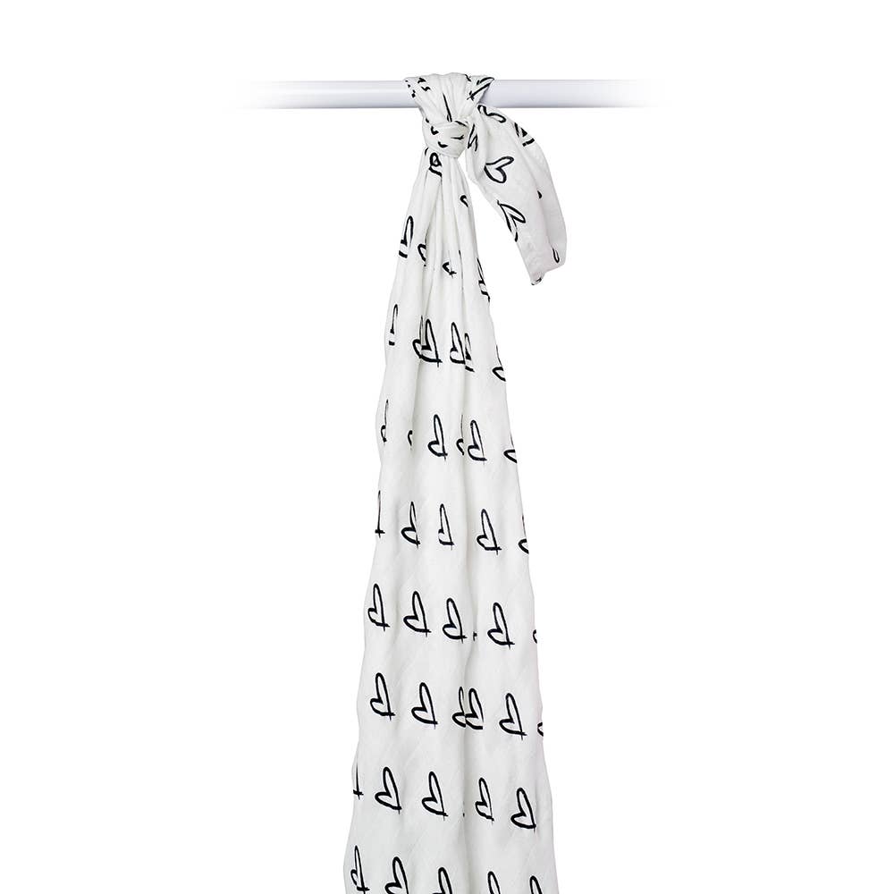 A white baby blanket with a black repeating sailboat pattern, tied at the top and hanging down against a plain white background.