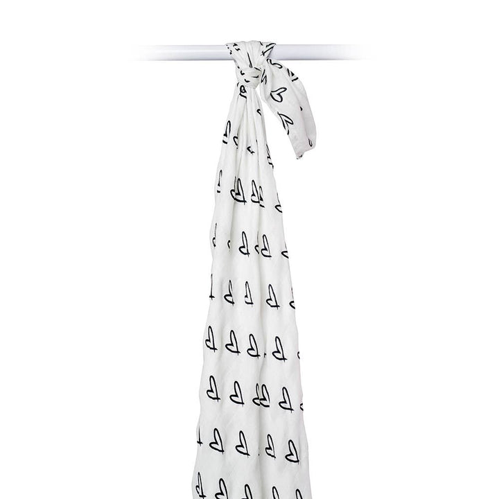 A white baby blanket with a black repeating sailboat pattern, tied at the top and hanging down against a plain white background.