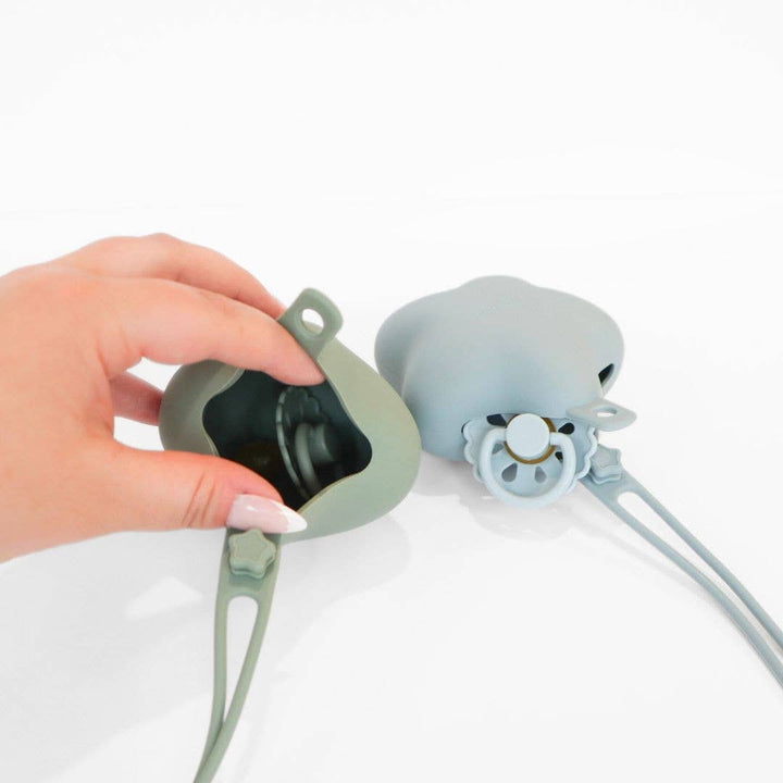 Two silicone earbud covers, one green and one blue, held by a hand on a white background.