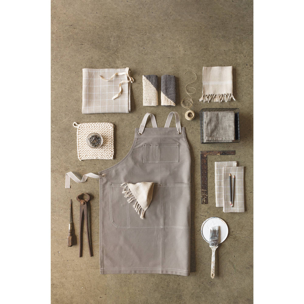 Gray apron with various kitchen items on a textured brown background
