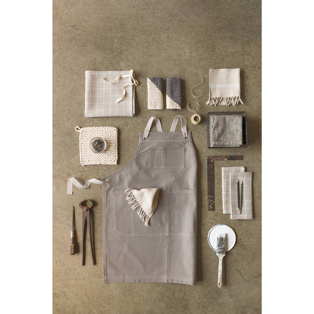 Gray apron with various kitchen items on a textured brown background