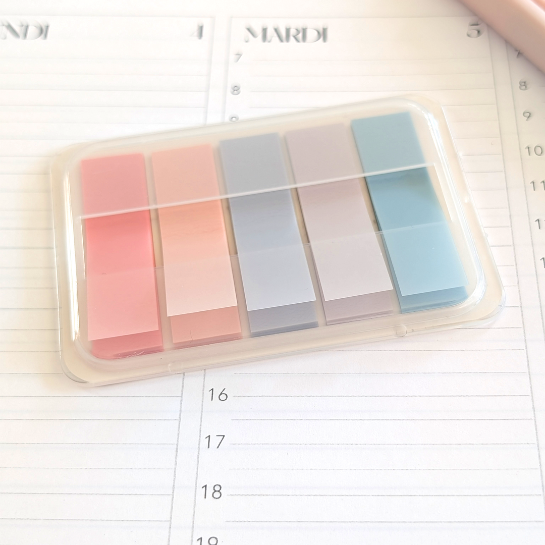 Set of colorful sticky notes in a clear plastic case on a planner page.