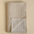 Folded fabric with brown and white stripes on a beige background