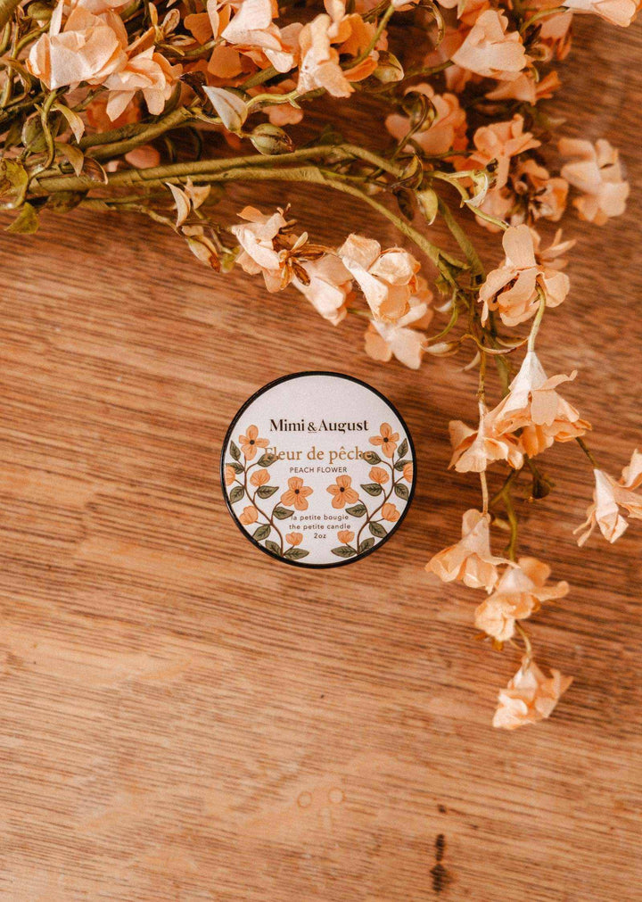 Small round container with floral design on a wooden surface with flowers