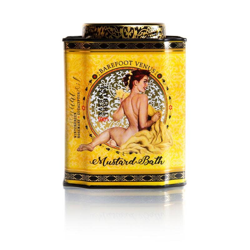 Barefoot Venus Mustard Bath Soak in a clear glass jar with a golden label, surrounded by mustard seeds and natural spa elements.