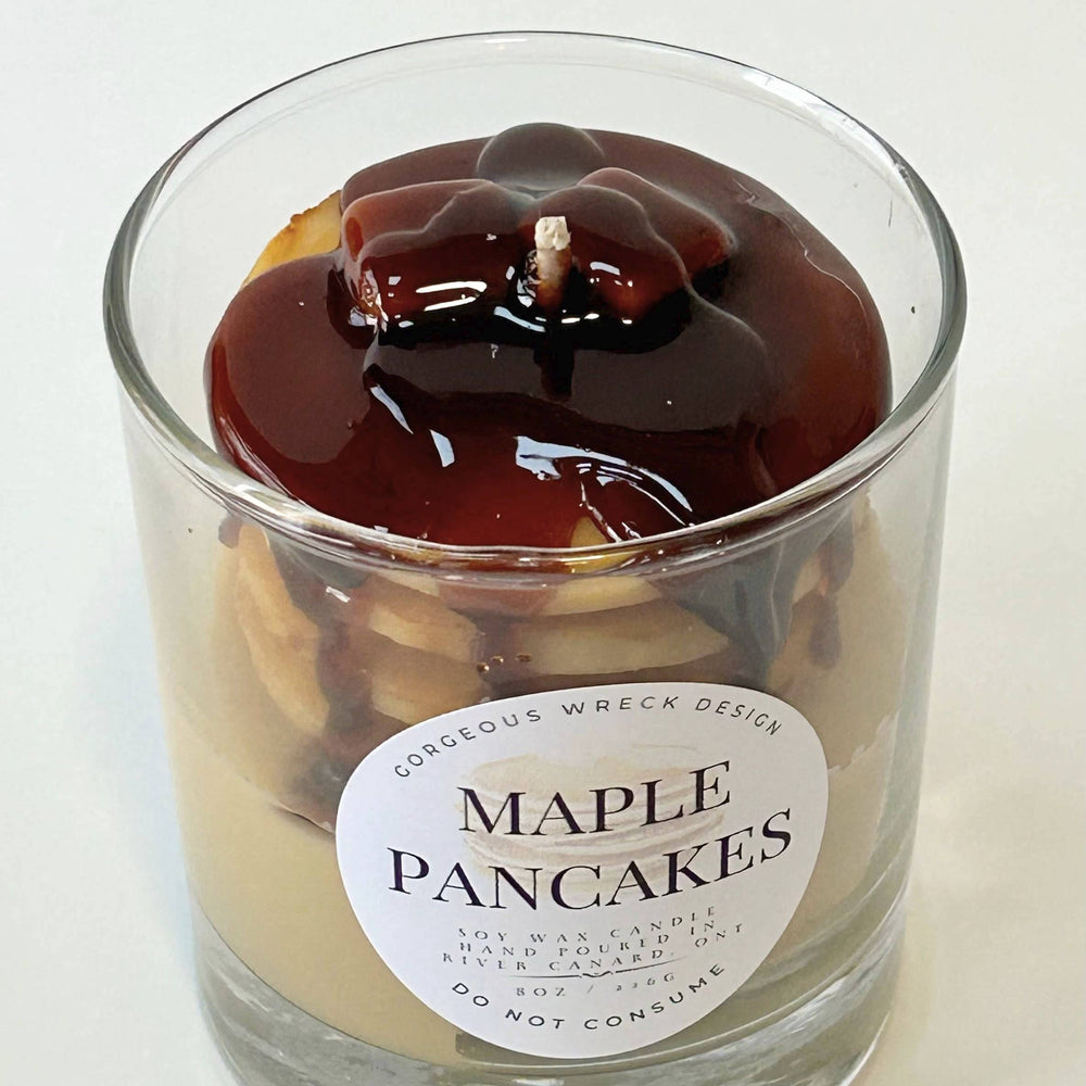 Candle in a glass jar labeled 'Maple Pancakes' on a white background