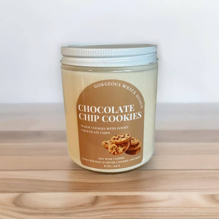 Jar of 'Chocolate Chip Cookies' candle on a wooden surface with a white background