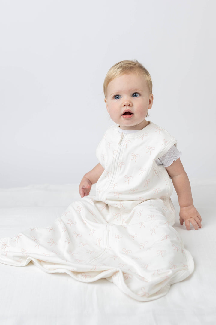 Baby in a white outfit sitting on a white background