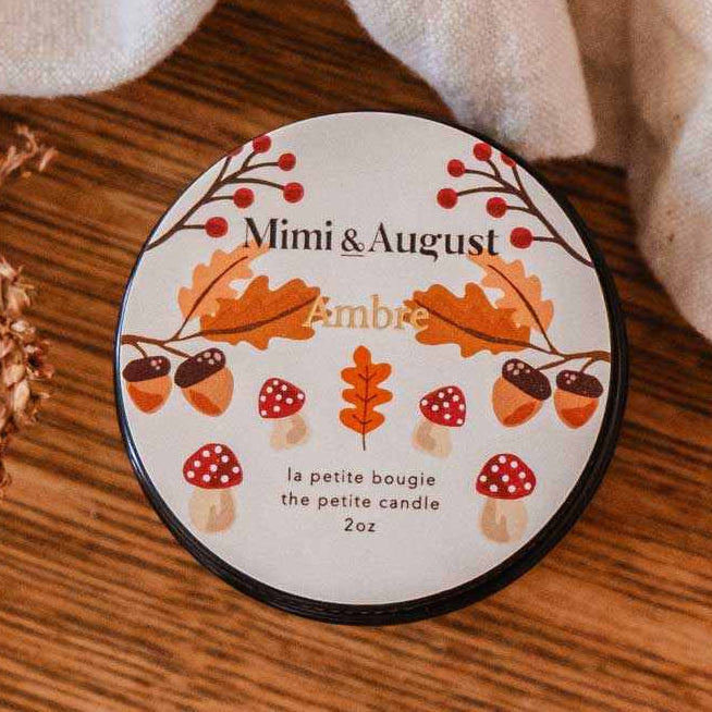 Decorative coaster with autumn design on a wooden surface with leaves and a candle.
