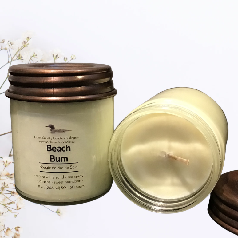 Two candles with bronze lids on a light background with floral elements