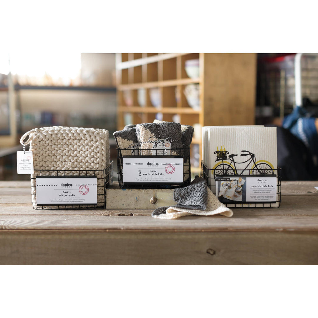 Three woven bags with tags on a wooden surface, blurred background