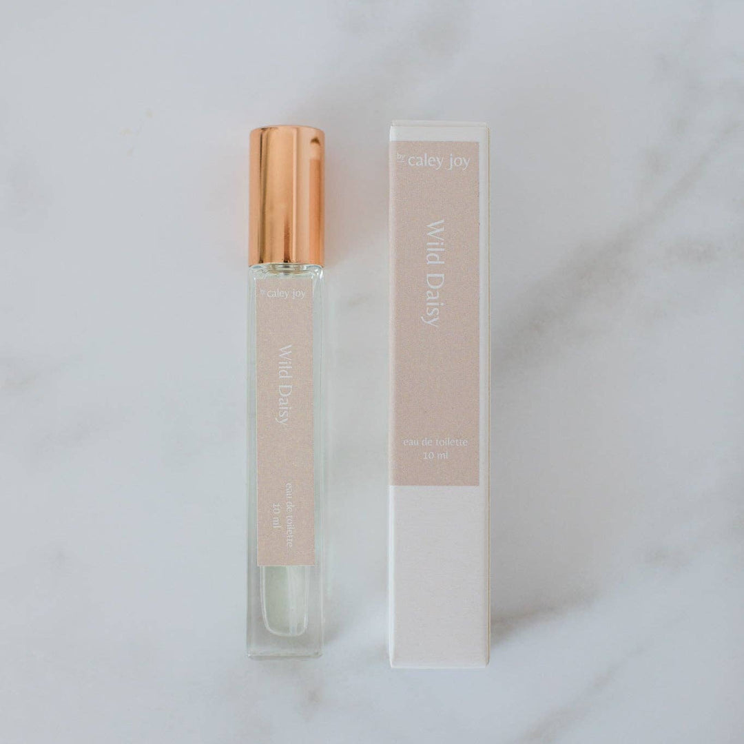 Perfume bottle with gold cap and packaging on a light gray background