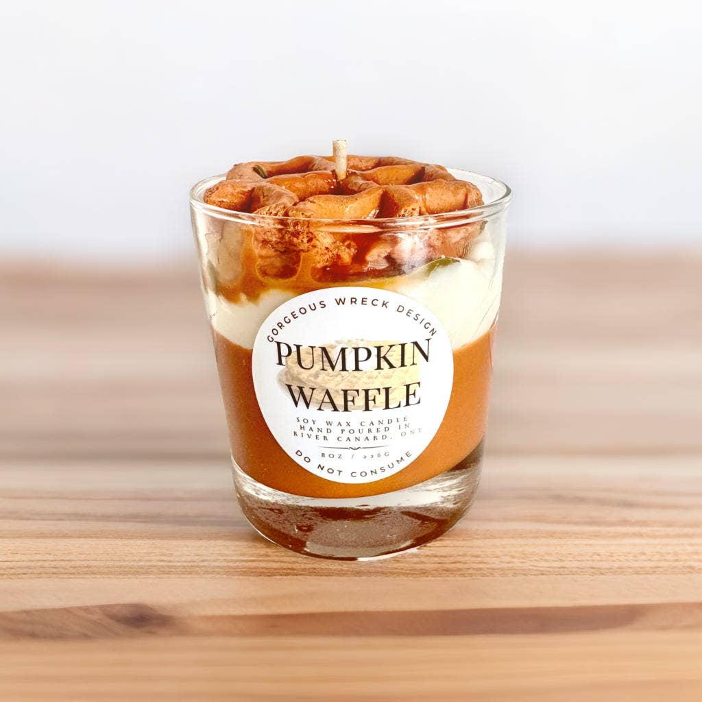 Candle in the shape of a pumpkin waffle with a label on a wooden surface