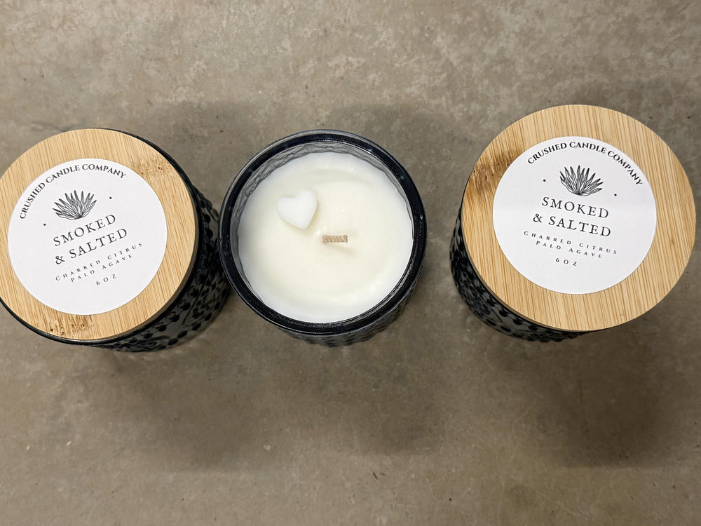 Three candles from Crudo Candle Company on a concrete surface