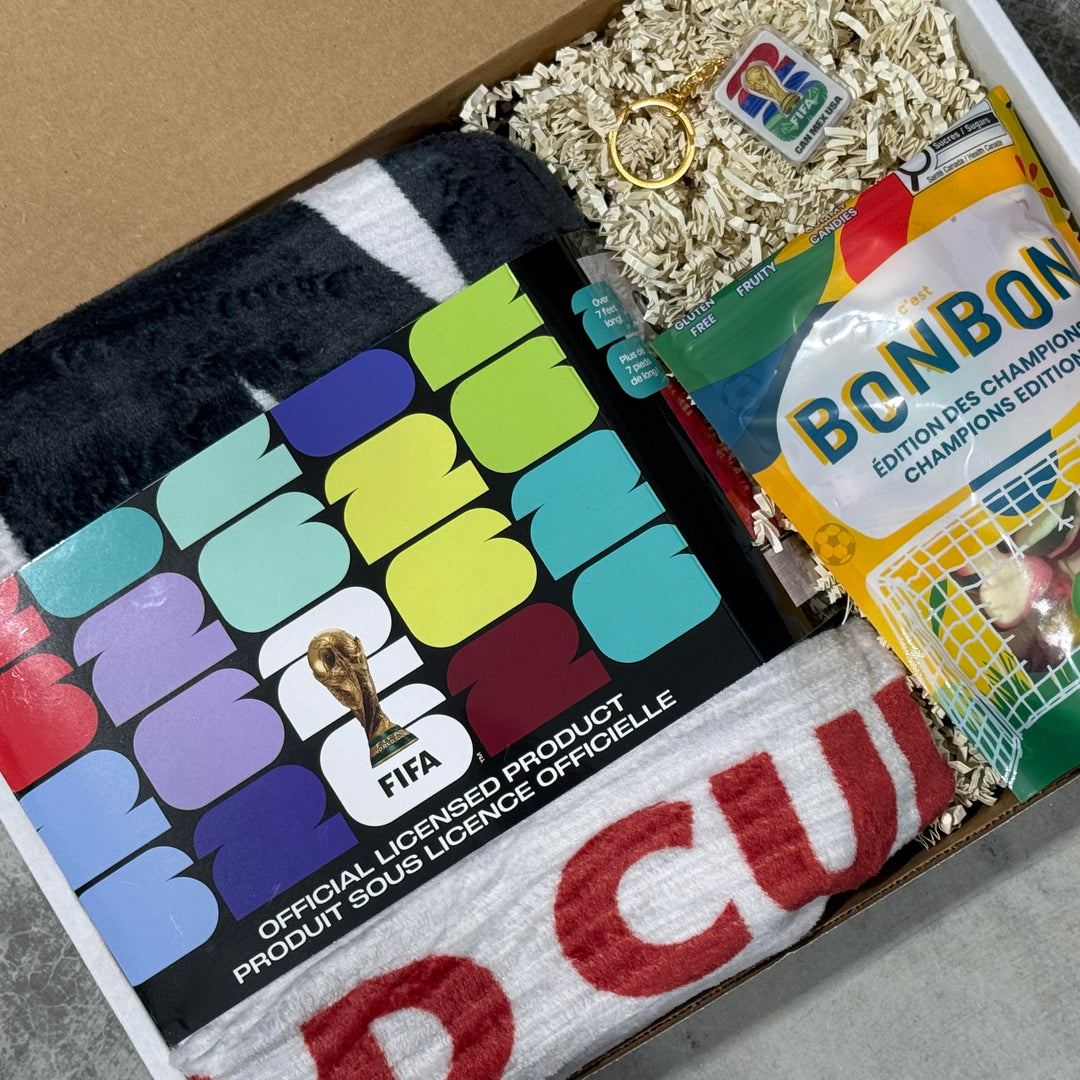 Box containing socks, a bag of candy, and a keychain with colorful branding.
